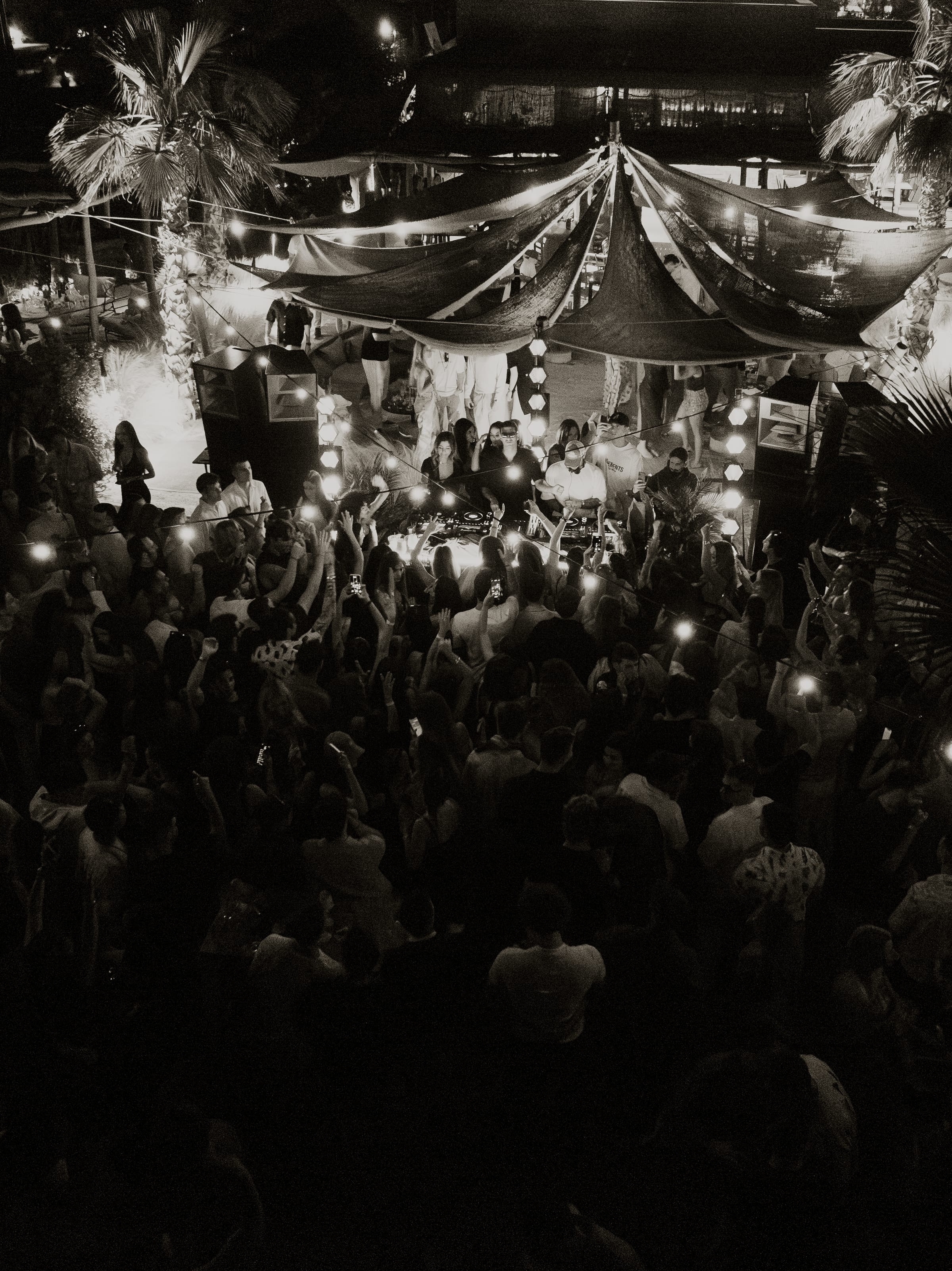A crowd dancing under string lights at night